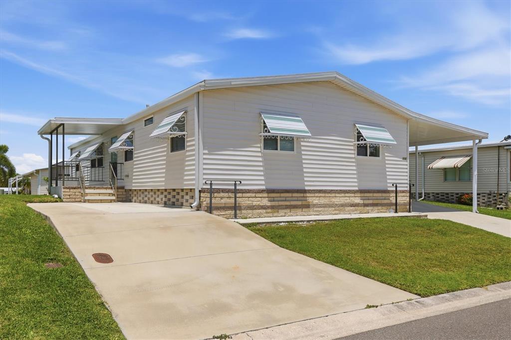 A single-story manufactured home with light siding, a concrete driveway, and a covered carport — 4308 13TH STREET E, ELLENTON, FL