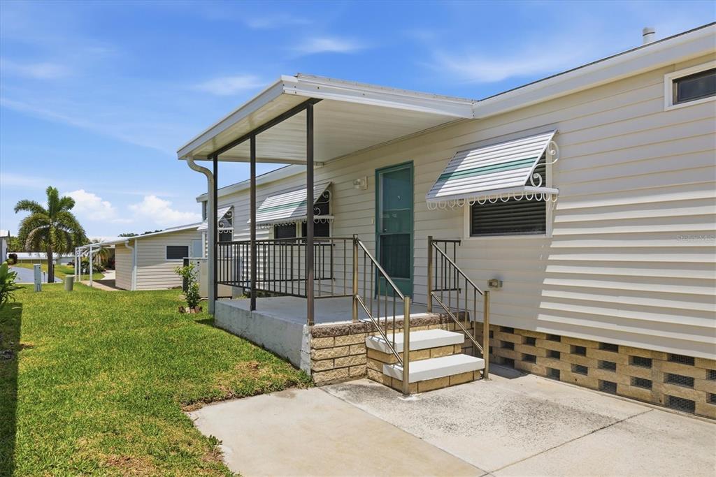 A mobile home exterior features a covered concrete porch with metal railings and stairs — 4308 13TH STREET E, ELLENTON, FL