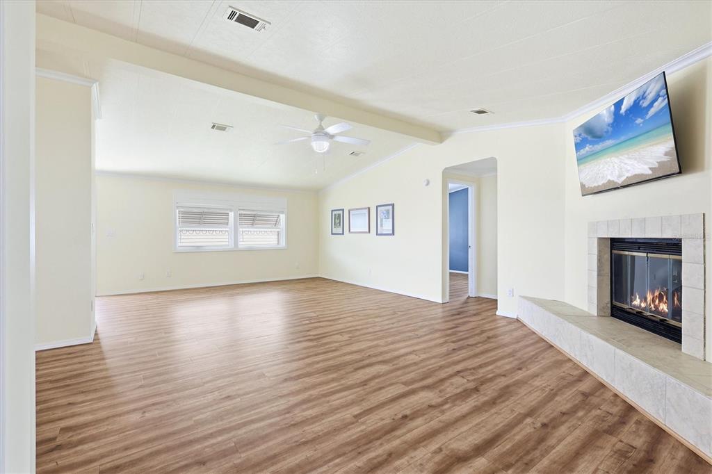 A spacious living room features light-colored walls, wood-look flooring, a ceiling fan, and a fireplace — 4308 13TH STREET E, ELLENTON, FL