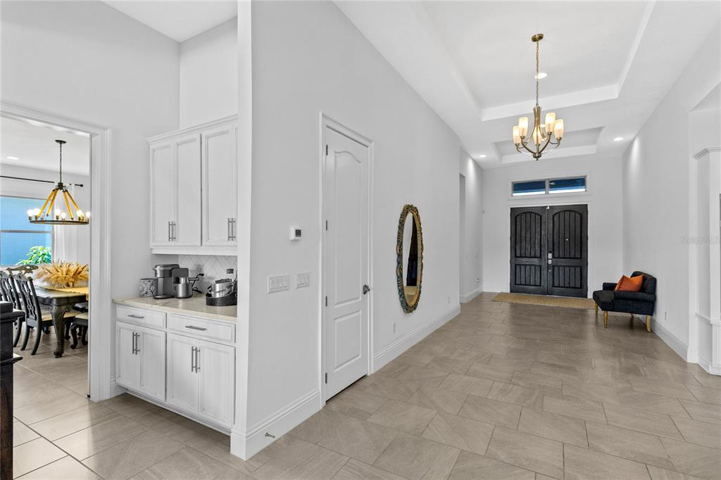 A bright entryway features tile flooring, a tray ceiling with a chandelier, and white cabinetry — 13167 ALDERLEY DRIVE, ORLANDO, FL