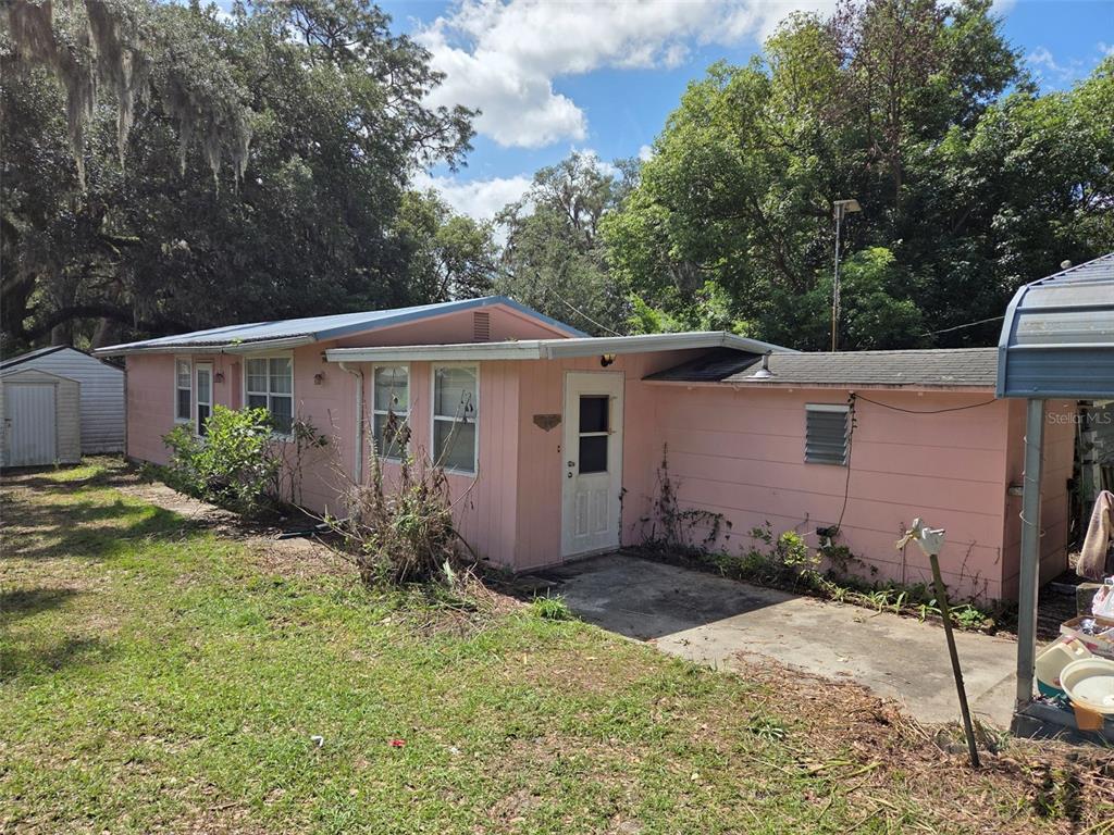 A pink, single-story house with a metal roof and a concrete patio area — 4534 SEABERG ROAD, ZEPHYRHILLS, FL