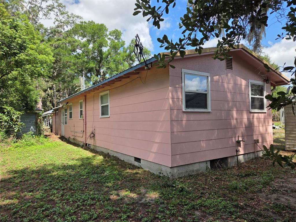 The exterior of a pink, single-story house with horizontal siding and a metal roof — 4534 SEABERG ROAD, ZEPHYRHILLS, FL