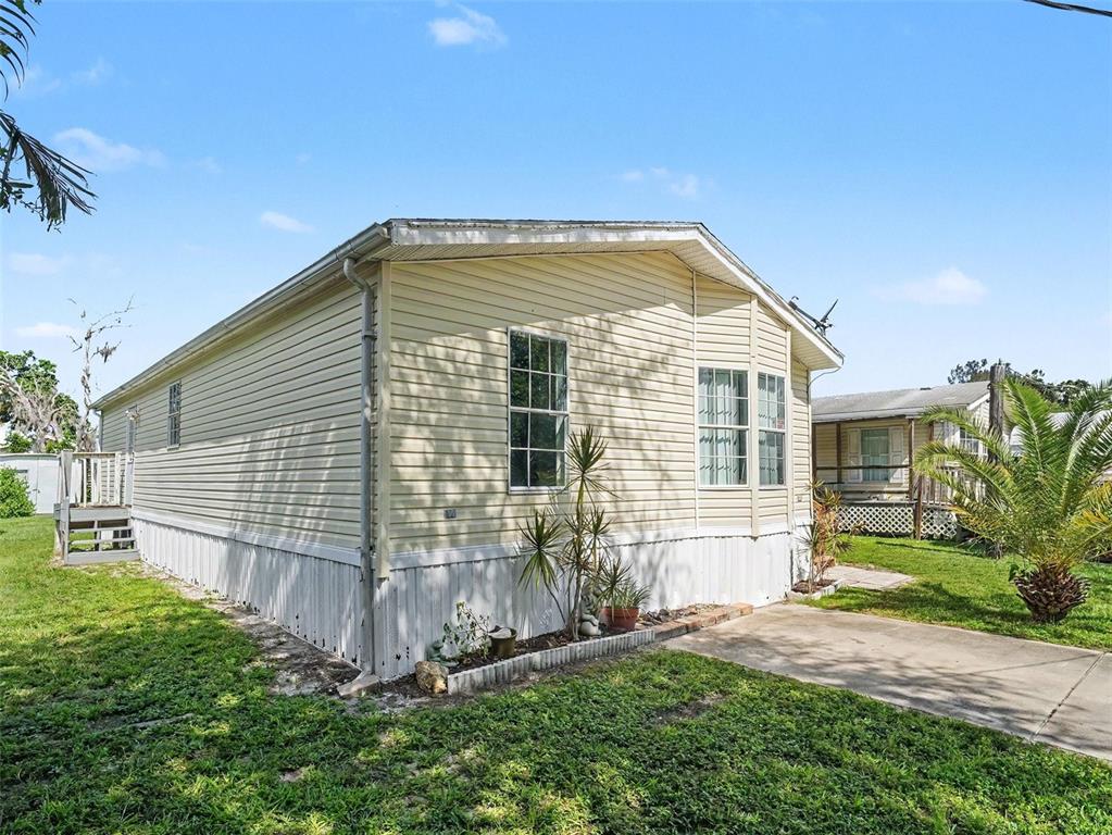 A light-colored manufactured home with vinyl siding sits on a grassy lot with palm trees — 4928 ELIZABETH AVENUE, SARASOTA, FL
