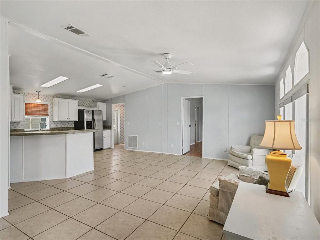 An open-concept living room and kitchen with tile flooring, white cabinetry, and a ceiling fan — 4928 ELIZABETH AVENUE, SARASOTA, FL