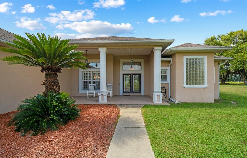 The exterior of a single-story house features a covered porch, white columns, and a palm tree — 5170 SE HIGHWAY 42, SUMMERFIELD, FL