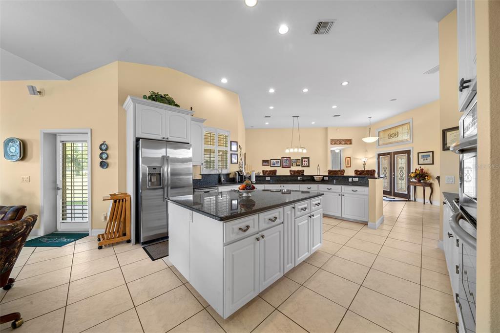 A kitchen with white cabinets, a granite-topped island, stainless steel appliances, and tile flooring — 5170 SE HIGHWAY 42, SUMMERFIELD, FL