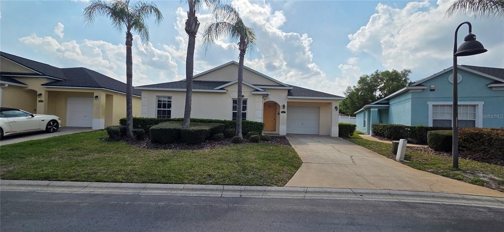 A single-story house with a beige exterior, a concrete driveway, and three palm trees — 528 RESERVE DRIVE, DAVENPORT, FL