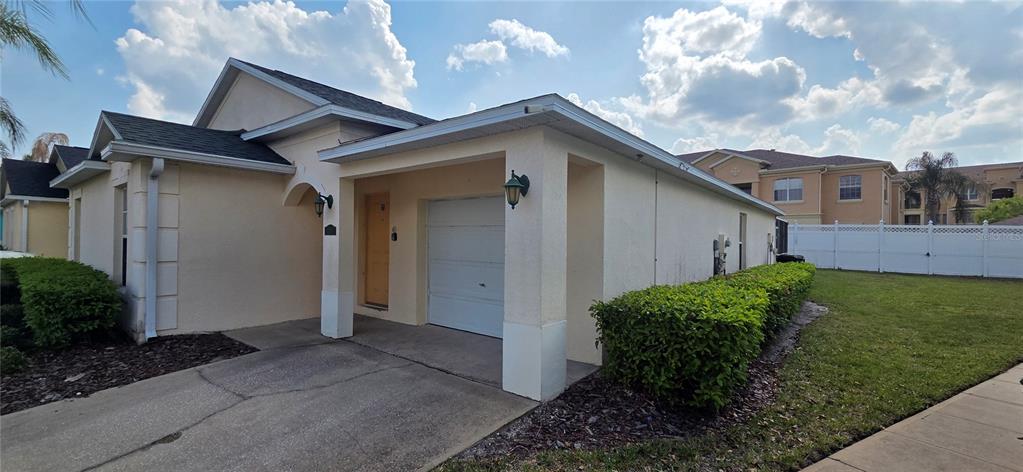 A single-story house with a beige stucco exterior, a small garage, and a front porch — 528 RESERVE DRIVE, DAVENPORT, FL