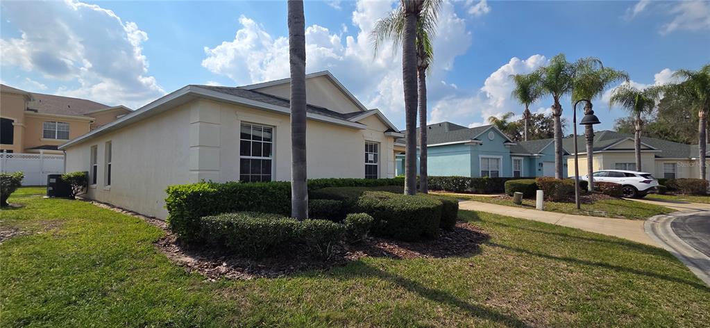 A side view of a beige single-story house with palm trees and manicured hedges — 528 RESERVE DRIVE, DAVENPORT, FL