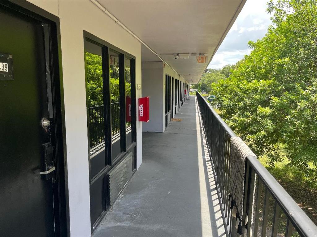An exterior walkway of a motel building features a black door, windows, and a fire extinguisher — 8421 S ORANGE BLOSSOM TRAIL UNIT 302, ORLANDO, FL