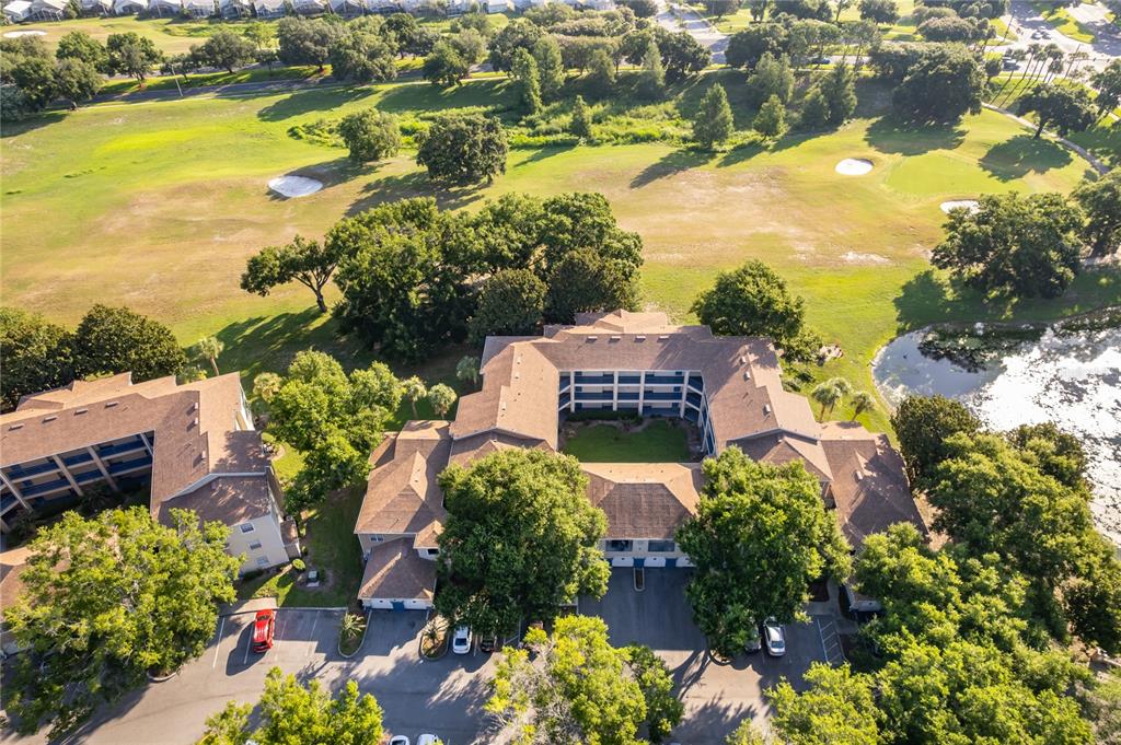 An aerial view shows a multi-story apartment complex with a central courtyard near a golf course — 7210 WESTPOINTE BOULEVARD UNIT 1312, ORLANDO, FL