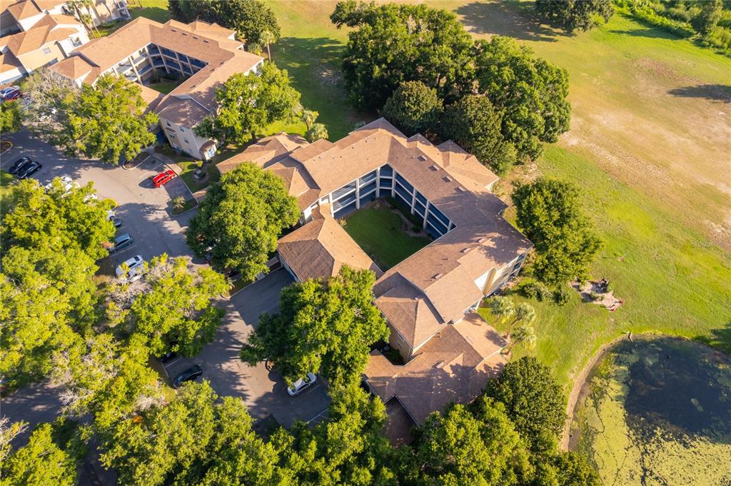 An aerial view shows a multi-story apartment building with a central courtyard and parking lot — 7210 WESTPOINTE BOULEVARD UNIT 1312, ORLANDO, FL