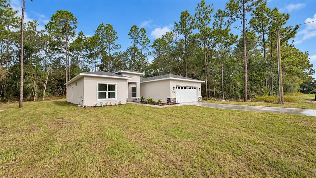 A single-story house with a white stucco exterior, stone accents, and a two-car garage — 9572 N SANDREE DRIVE, CITRUS SPRINGS, FL