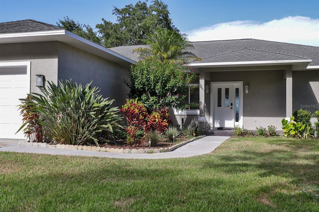 A single-story house with a gray exterior, a white front door, and a landscaped front yard — 2437 SWORDFISH LANE, EDGEWATER, FL