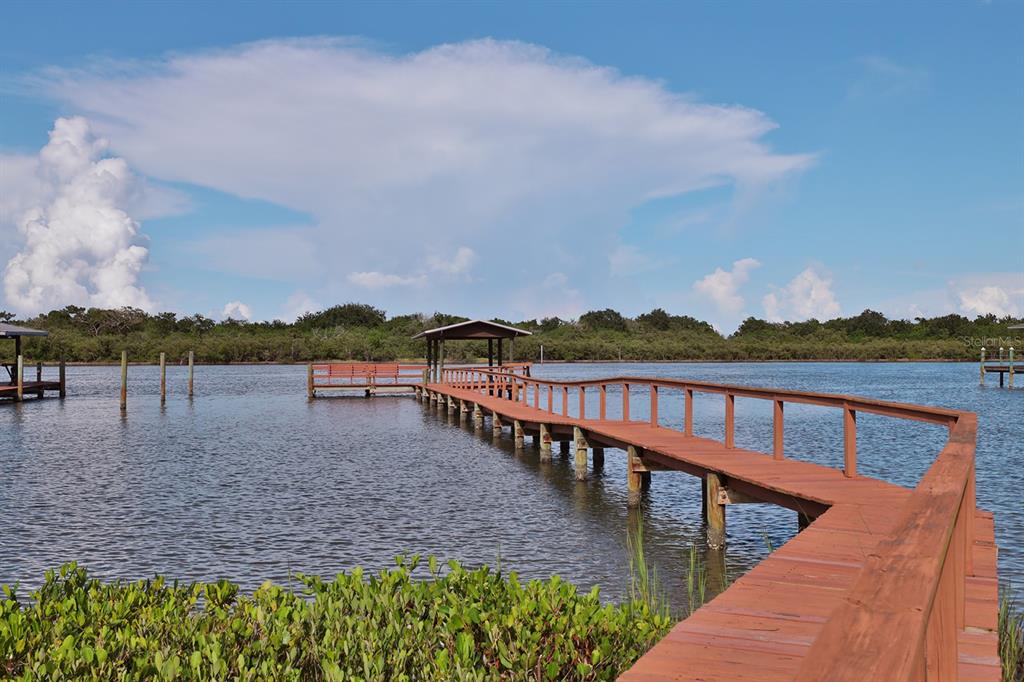 A wooden pier with a covered gazebo extends over a calm body of water — 2437 SWORDFISH LANE, EDGEWATER, FL
