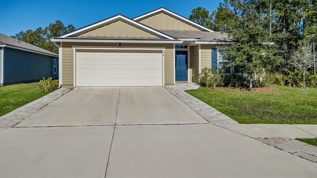 A tan single-story house features a two-car garage, a blue front door, and a driveway — 176 FALCON RIDGE, ST AUGUSTINE, FL