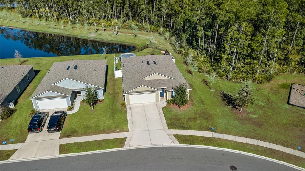 An aerial view shows two suburban houses with driveways, lawns, and a nearby pond — 176 FALCON RIDGE, ST AUGUSTINE, FL