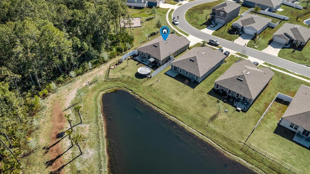 An aerial view shows a suburban house with a backyard pool bordering a small pond — 176 FALCON RIDGE, ST AUGUSTINE, FL