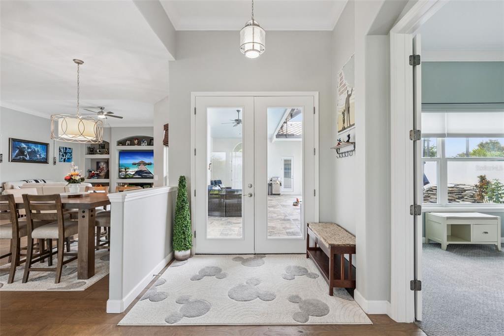 An entryway with a Mickey Mouse patterned rug, double glass doors, and a dining area — 2270 CALLAWAY COURT, DAVENPORT, FL