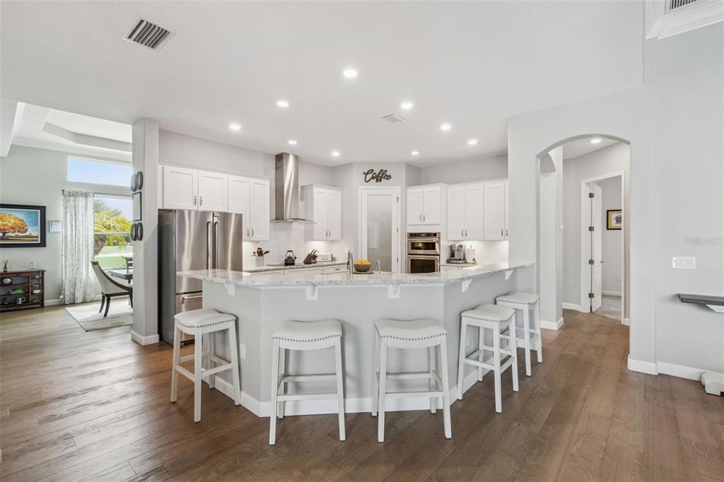 A kitchen with white cabinets, stainless steel appliances, a breakfast bar, and hardwood flooring — 2270 CALLAWAY COURT, DAVENPORT, FL
