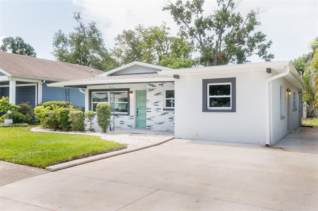 A single-story house with a white brick facade, a teal front door, and a driveway — 4220 W UNION STREET, TAMPA, FL