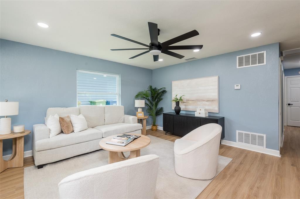 A living room features light blue walls, a white sofa, two armchairs, and wood flooring — 4220 W UNION STREET, TAMPA, FL