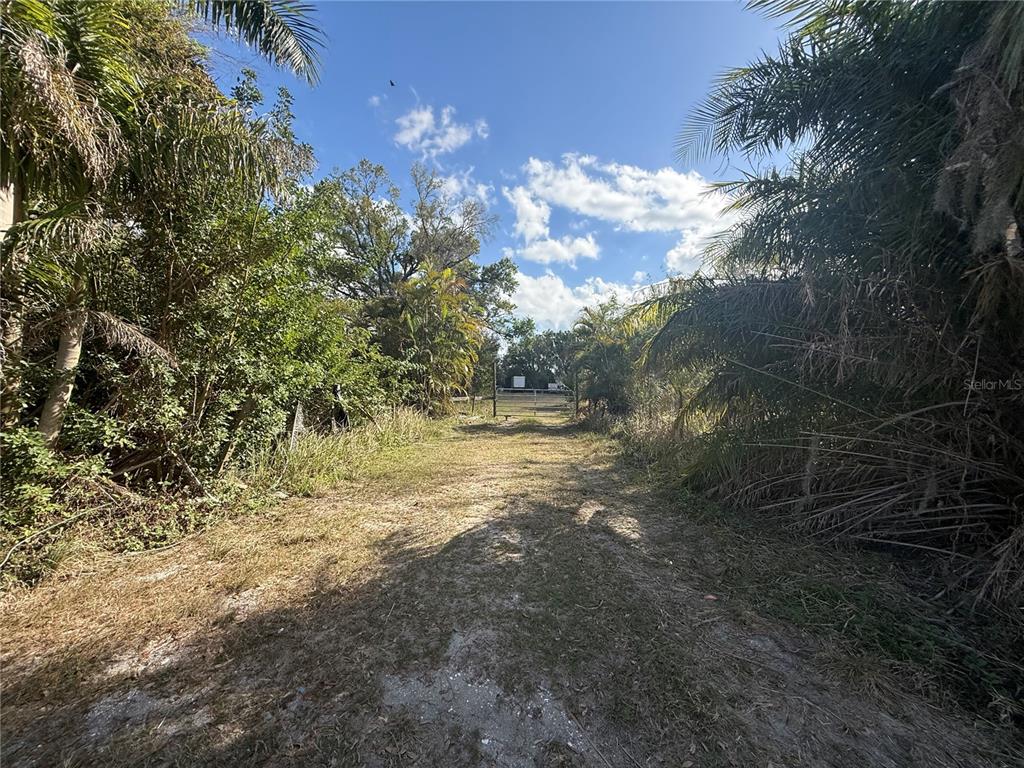A dirt path leads through dense trees and foliage toward a gated entrance — 11959 MOCCASIN WALLOW ROAD, PARRISH, FL