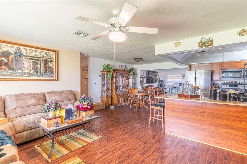 An open-concept living room and kitchen feature wood-look flooring, a ceiling fan, and wooden cabinetry — 305 CLOVERLEAF ROAD, LAKE PLACID, FL