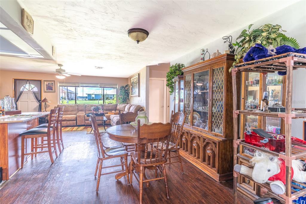 An open-concept living and dining area features wood-look flooring, a wooden hutch, and bar seating — 305 CLOVERLEAF ROAD, LAKE PLACID, FL