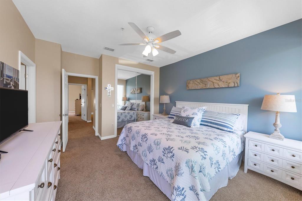 A bedroom features a king bed, white furniture, a ceiling fan, and a blue accent wall — 8272 HARBORSIDE CIRCLE, ENGLEWOOD, FL