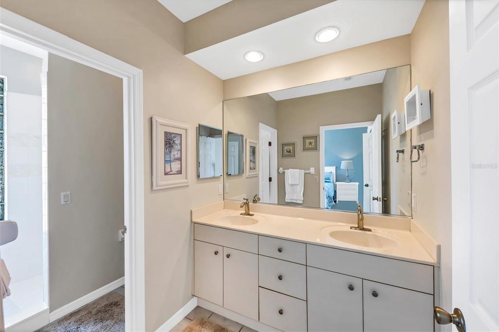 A bathroom features a double vanity with beige countertops, light-colored cabinets, and a large mirror — 8272 HARBORSIDE CIRCLE, ENGLEWOOD, FL