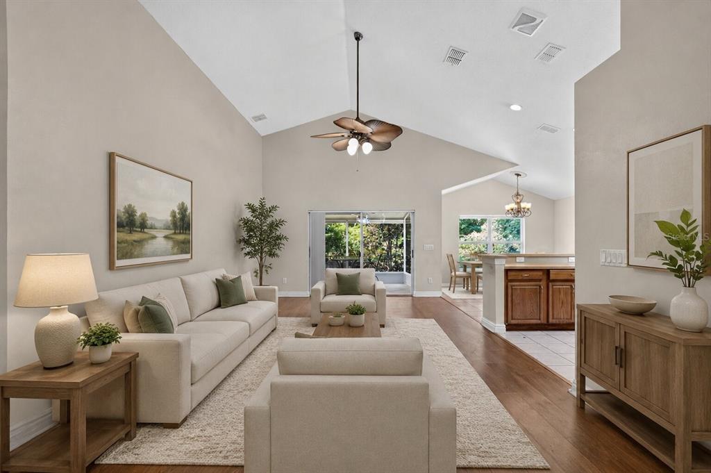 A living room with a vaulted ceiling, beige sofa, area rug, and wood flooring — 2887 DOE RUN TRAIL, ORANGE CITY, FL
