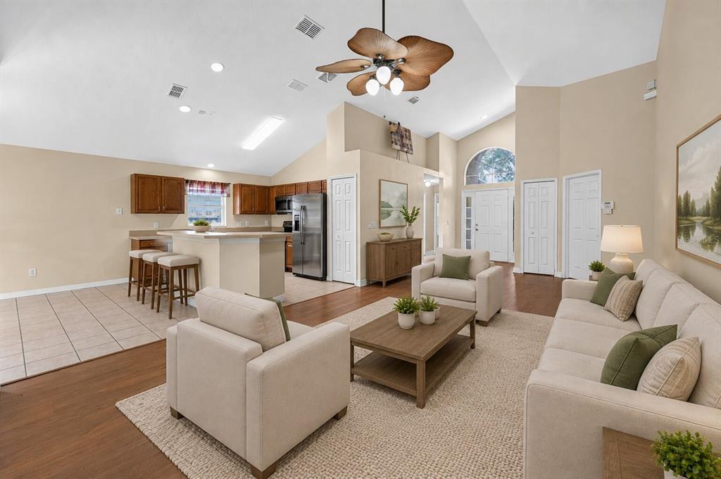 An open-concept living room with a kitchen, vaulted ceilings, and a ceiling fan — 2887 DOE RUN TRAIL, ORANGE CITY, FL