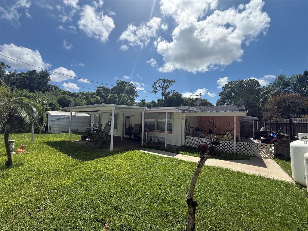 A single-story house with a covered patio, white siding, and a grassy backyard — 1650 AQUA LANE, HOLIDAY, FL