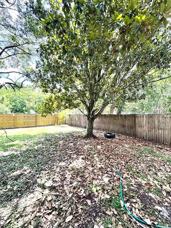 A large tree stands in a backyard covered with fallen leaves, enclosed by wooden fencing — 2776 RIVER RIDGE DRIVE, ORLANDO, FL
