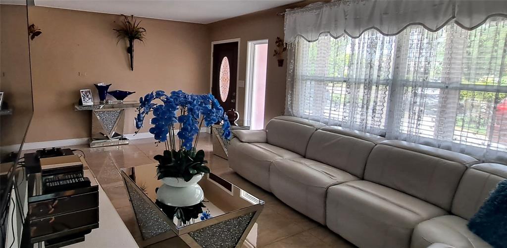 A living room features a white leather sectional sofa, a glass coffee table, and blue flowers — 3964 22ND AVENUE N, ST PETERSBURG, FL