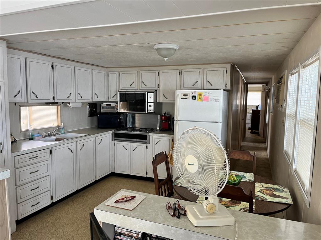 A kitchen with white cabinets, a white refrigerator, and a small dining table with chairs — 11128 102ND WAY UNIT 225, LARGO, FL