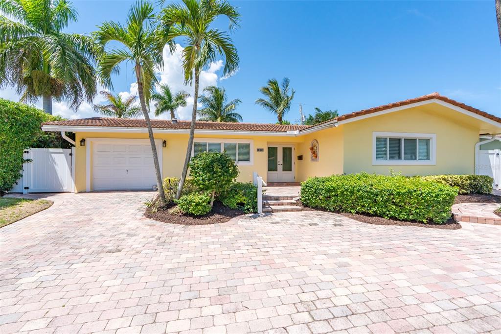 A yellow single-story house with a paved driveway, a garage, and palm trees in front — 1271 SW 9TH STREET, BOCA RATON, FL