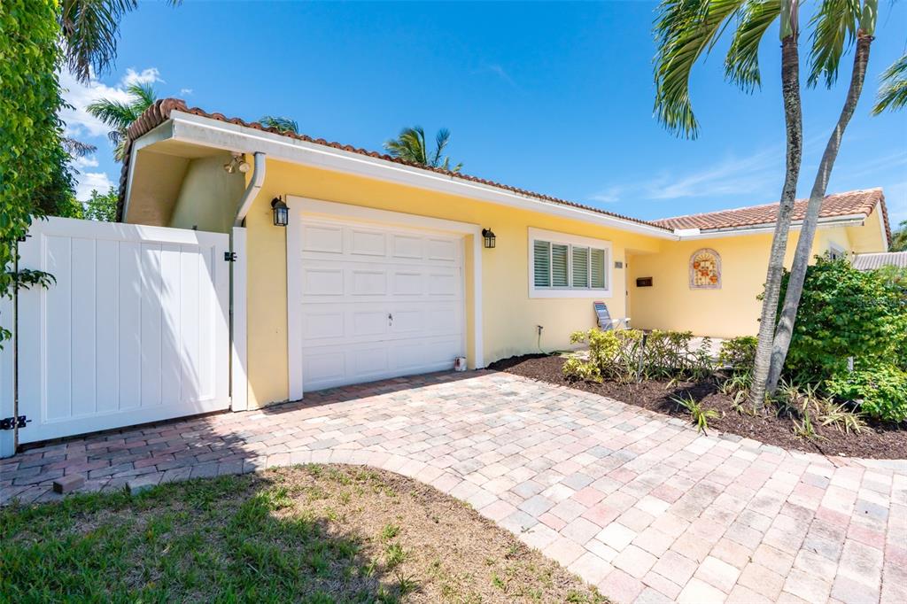 A yellow house with a white garage door, a paved driveway, and a white gate — 1271 SW 9TH STREET, BOCA RATON, FL