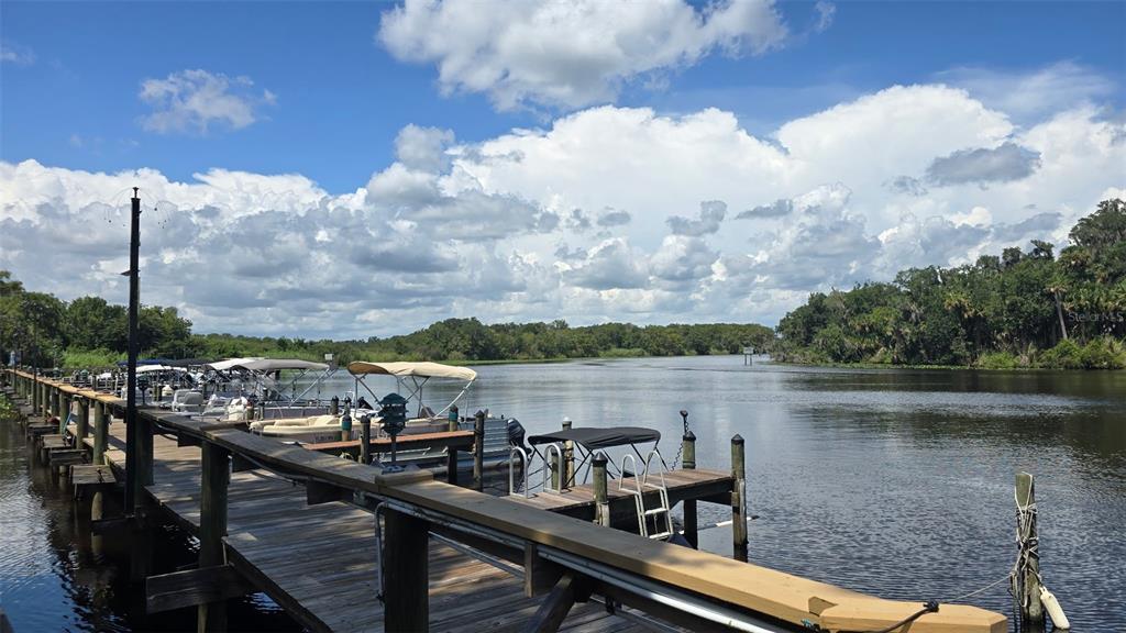 A wooden dock extends into a river with several pontoon boats moored along the side — 213 SHER LANE UNIT 1, DEBARY, FL