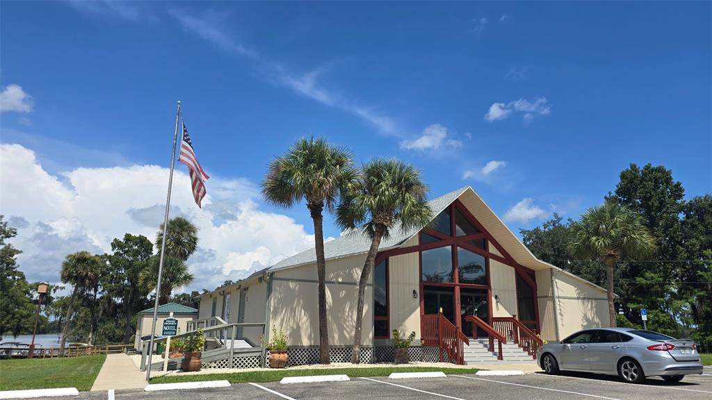 A light-colored building with a gabled roof and palm trees stands next to a parking lot — 213 SHER LANE UNIT 1, DEBARY, FL