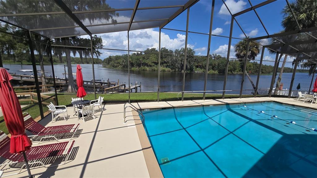 A screened-in pool deck overlooks a lake with a wooden dock and palm trees — 213 SHER LANE UNIT 1, DEBARY, FL