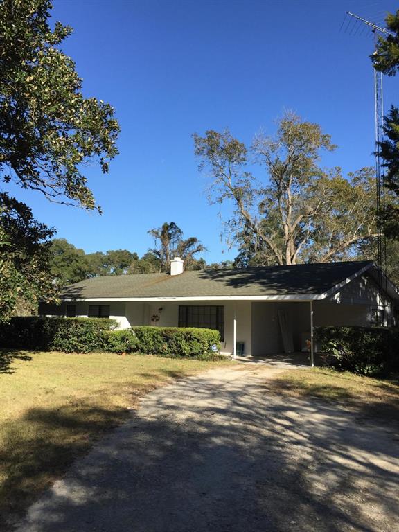 A single-story house with a white exterior, a dark shingled roof, and an attached carport — 7237 NE 33rd COURT, ANTHONY, FL