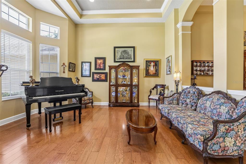 A living room features a grand piano, floral sofa, wooden coffee table, and a display cabinet — 2431 PONKAN SUMMIT DRIVE, APOPKA, FL
