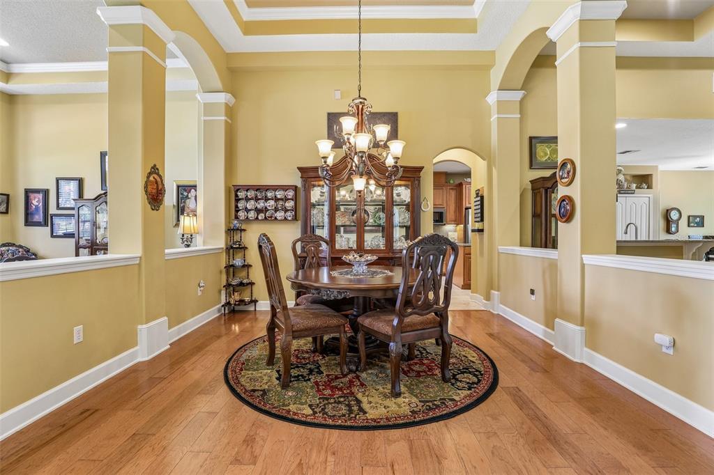 A formal dining room features a round wooden table, chairs, and a china cabinet — 2431 PONKAN SUMMIT DRIVE, APOPKA, FL