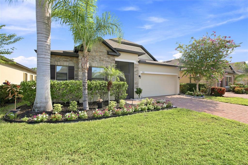 A single-story house with a stone facade, a two-car garage, and a landscaped front yard — 3987 RIVER BANK WAY, PORT CHARLOTTE, FL