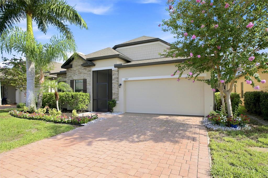 A one-story house with a beige stucco exterior, stone accents, and a paved driveway — 3987 RIVER BANK WAY, PORT CHARLOTTE, FL