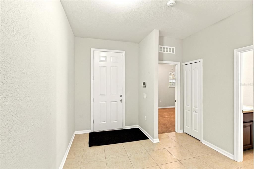 An entryway with a white front door, tile flooring, and a closed closet door — 3987 RIVER BANK WAY, PORT CHARLOTTE, FL