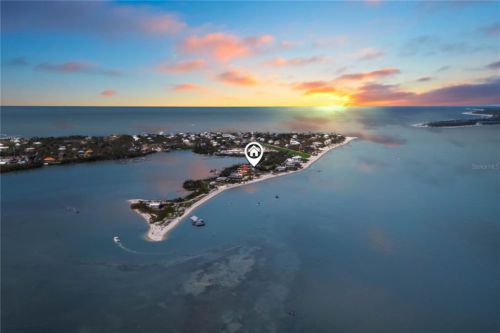 An aerial view shows a coastal island with houses surrounded by water at sunset — 4281 POINT HOUSE TRAIL, CAPTIVA, FL