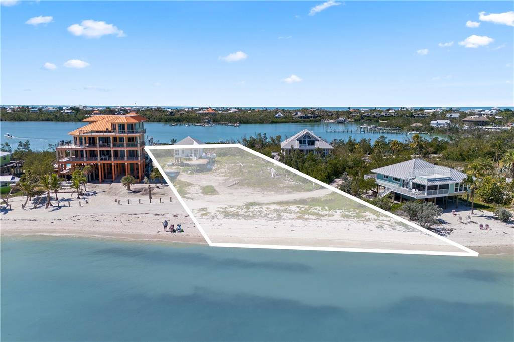 An aerial view shows a vacant beachfront lot situated between two elevated houses — 4281 POINT HOUSE TRAIL, CAPTIVA, FL